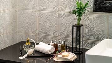 A bathroom vanity with a black countertop, a white towel, a glass bottle, and a small potted plant.