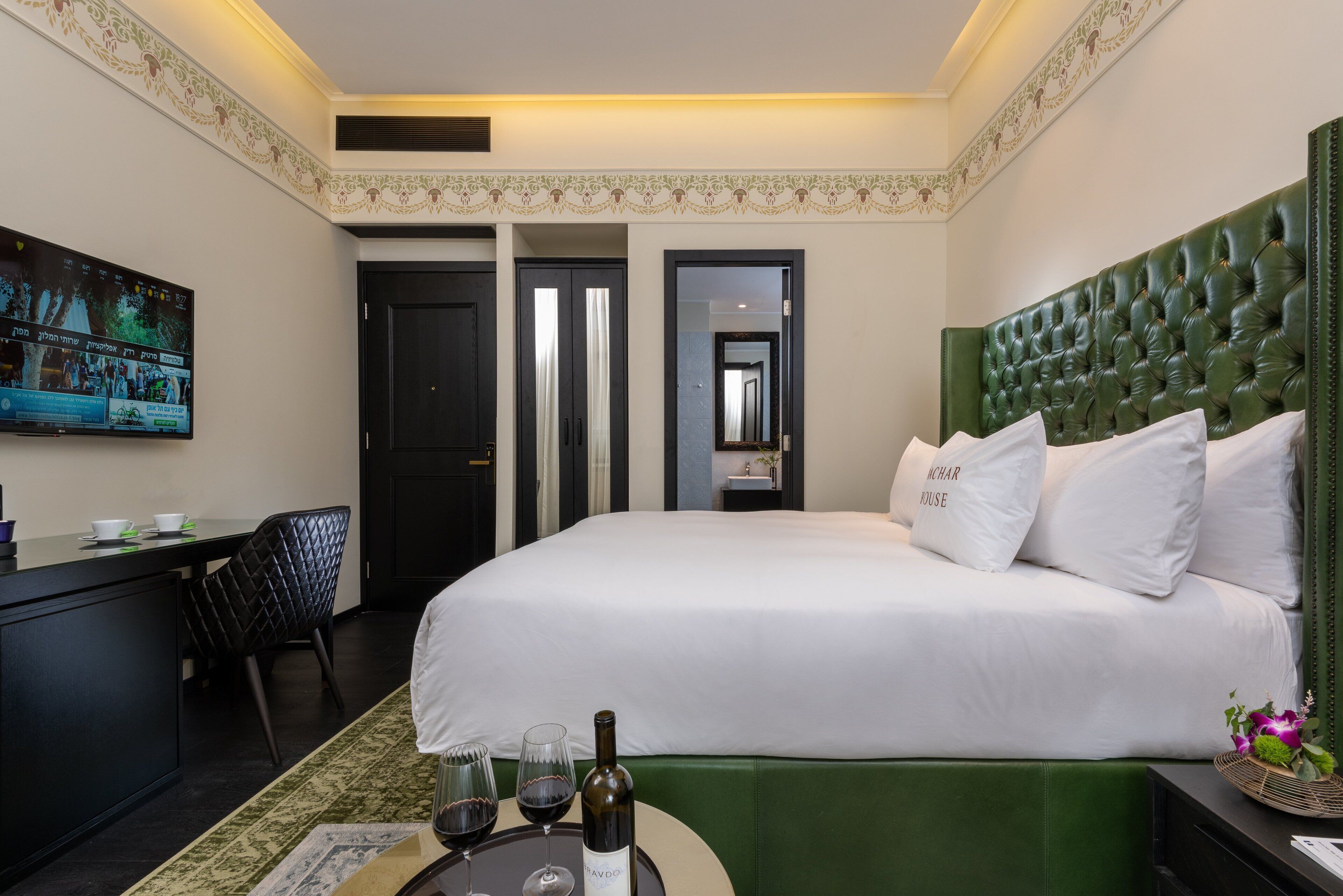 Una habitación de hotel con una cama grande, un escritorio con televisor y un área de comedor.