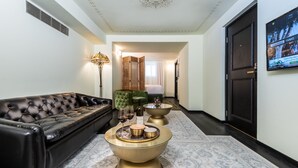 Una sala de estar moderna con un sofá de cuero negro, una mesa de centro dorada con objetos decorativos y un sillón verde.
