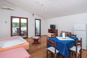 Une chambre avec deux lits, une table à manger avec des chaises, un téléviseur et un réfrigérateur.