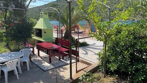 A patio area with a barbecue grill, picnic table, and chairs.