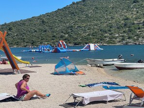 Une plage avec des toboggans aquatiques gonflables, une tente et des bateaux.
