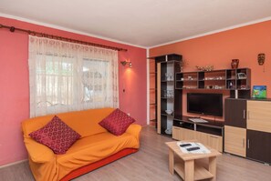 Un salon avec un canapé, un téléviseur, un meuble et une petite table.