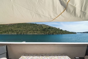 A balcony with a view of a lake and a hill.