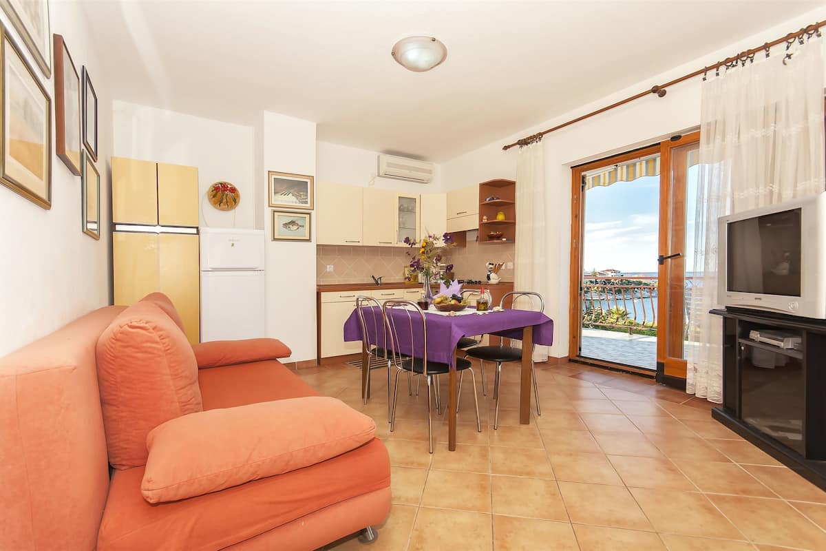 Een ruimtelijk ingerichte leefruimte met een bank, eettafel, keuken en een balkon met uitzicht.