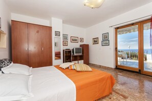 A bedroom with a bed, wardrobe, television, and a balcony with a view.
