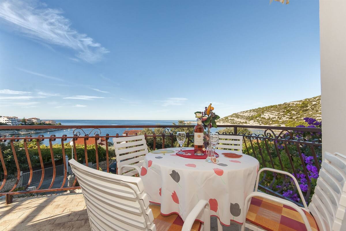 Een balkon met een tafel voor twee, met uitzicht op de kust.