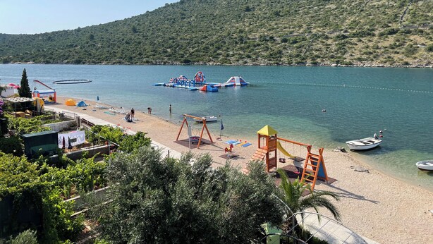 A beach with a playground, a boat, and a hill in the background.