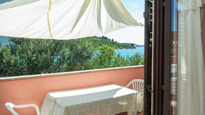 A balcony with a table and chairs, a white canopy, and a view of greenery and water.