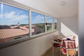 Varanda com vista para uma cidade, uma mesa com toalha e duas cadeiras.
