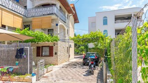 A narrow street with a parked motorcycle, a car, and a building with a balcony.