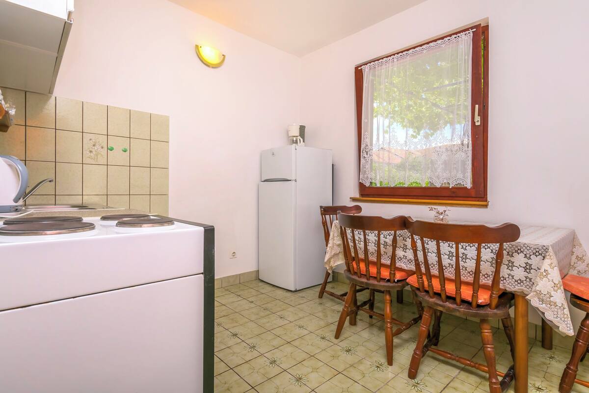 A kitchen with a stove, refrigerator, and dining table with chairs.