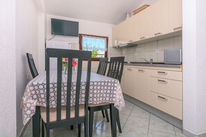 Keittiössä on ruokapöytä, tuoleja, televisio ja kaappeja.