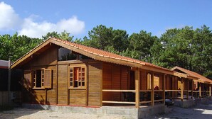 Fileira de cabanas de madeira com um caminho de cascalho e árvores ao fundo.