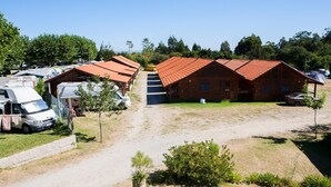 Um camping com veículos recreativos, cabanas de madeira e uma trilha de terra.