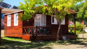 Uma pequena cabana de madeira com varanda e uma árvore na frente.