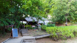 Une terrasse en bois mène à un espace extérieur abrité, aménagé avec des sièges et doté d’un tableau noir servant de menu.