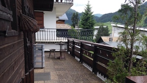 Un balcon avec une table et des chaises, une clôture en bois et une vue sur un paysage montagneux.