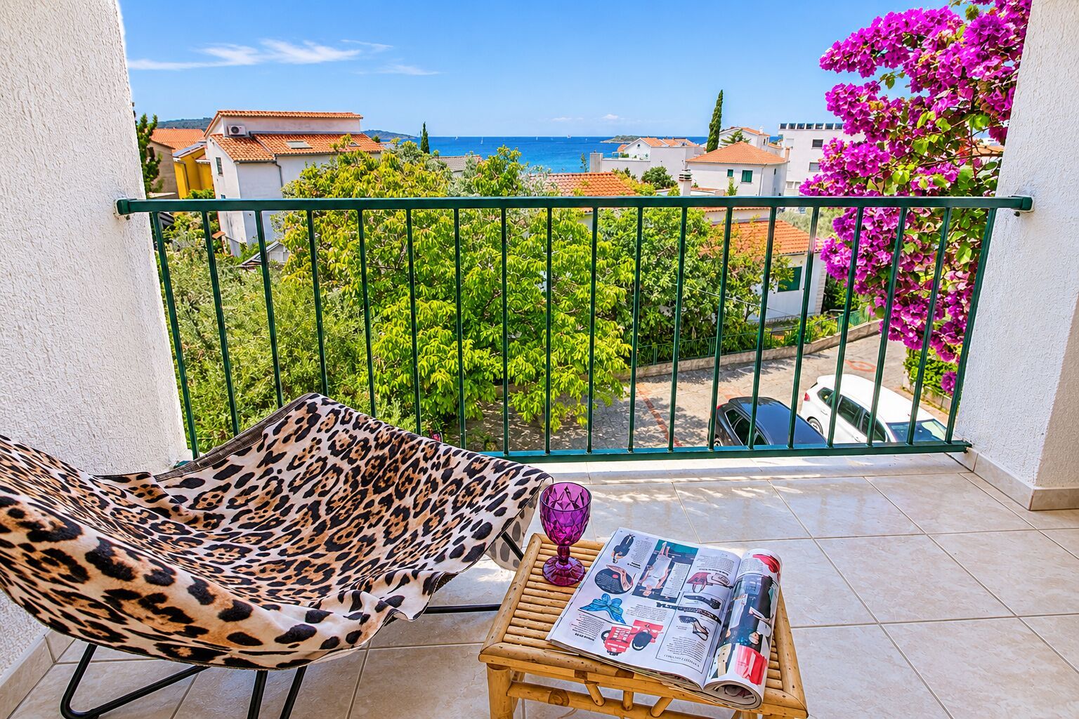 A balcony with a leopard print chair, a wooden table, and a magazine.