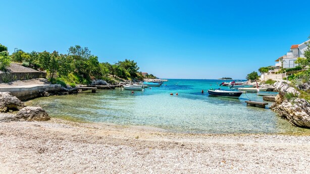 A coastal scene with clear water, boats, and rocky terrain.