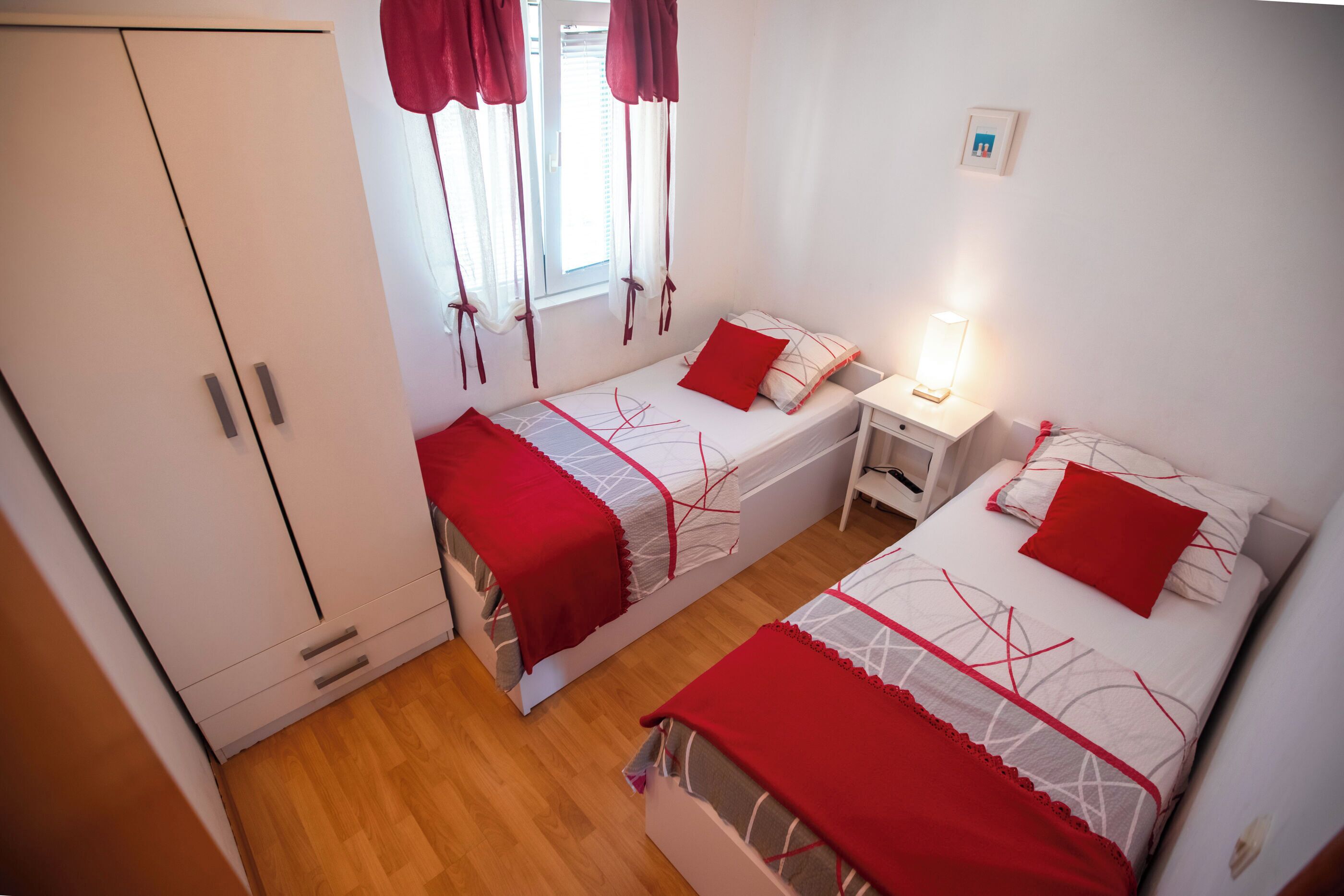 Une chambre avec deux lits, une armoire et une fenêtre avec des rideaux.
