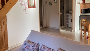 Un dormitorio con cama, una escalera de madera y una cocina visible a través de una puerta abierta.