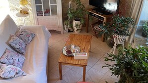 Una sala de estar acogedora con una pared de piedra, una mesa de centro de madera, un sillón rojo y un televisor.