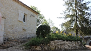 Un edificio de piedra con una ventana y un muro de piedra con plantas.