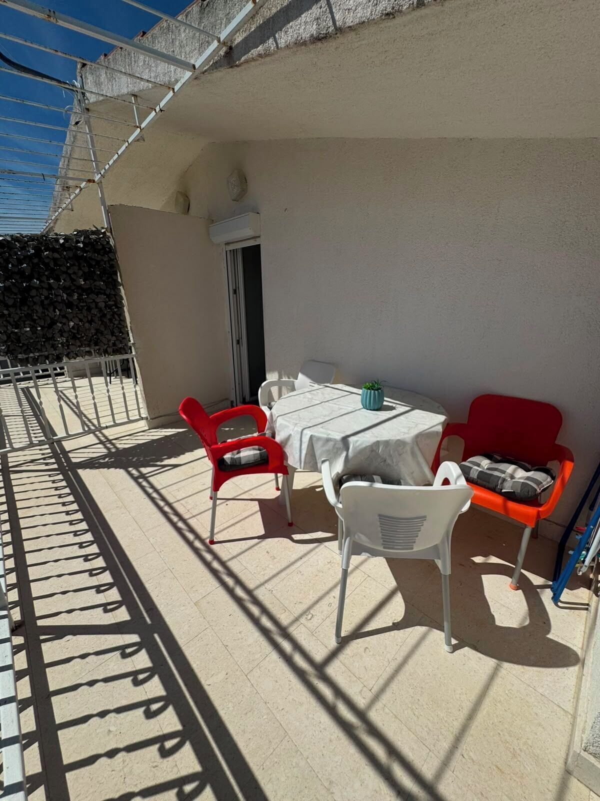 Ein Balkon mit Tisch, Stühlen, einer Tür und einem Metallgeländer.