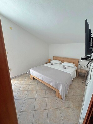 A bedroom with a bed, a TV, and a small table.