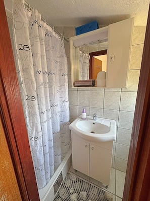 A bathroom with a white sink, a mirror above it, and a shower curtain with 'spirit' text.