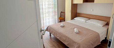 Quarto com cama, cadeira, guarda-roupa e janela com cortinas.