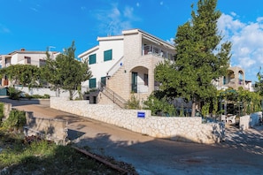 Un edificio de dos pisos con un muro de piedra, un balcón y una escalera.