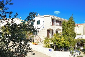 A two-story building with a stone wall, a balcony, and a clear blue sky.