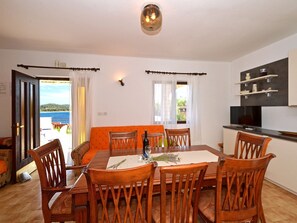 Uma sala de jantar com uma mesa, cadeiras e uma televisão.