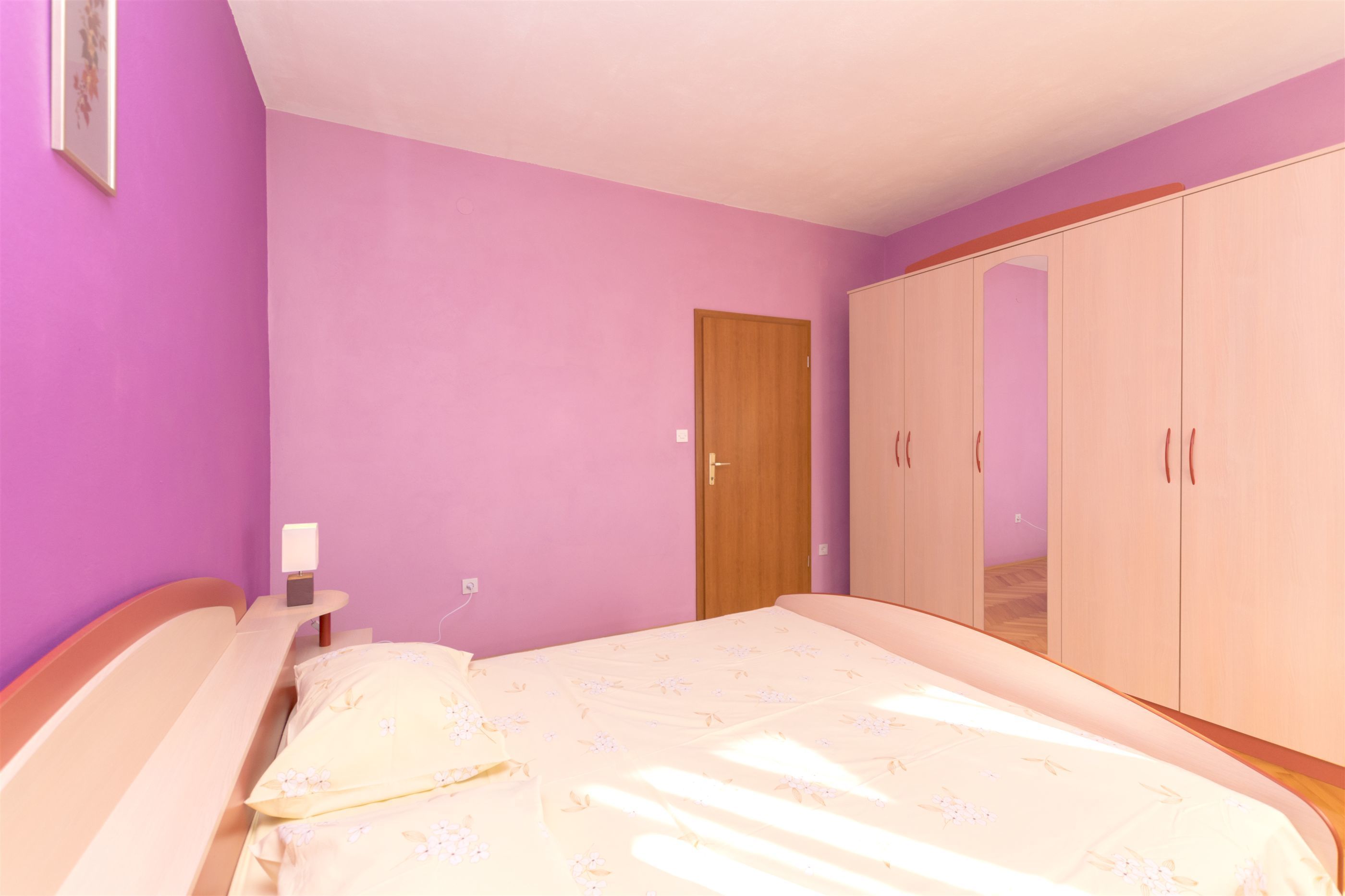 Une chambre à coucher avec un lit, une armoire et une table de chevet avec une lampe.
