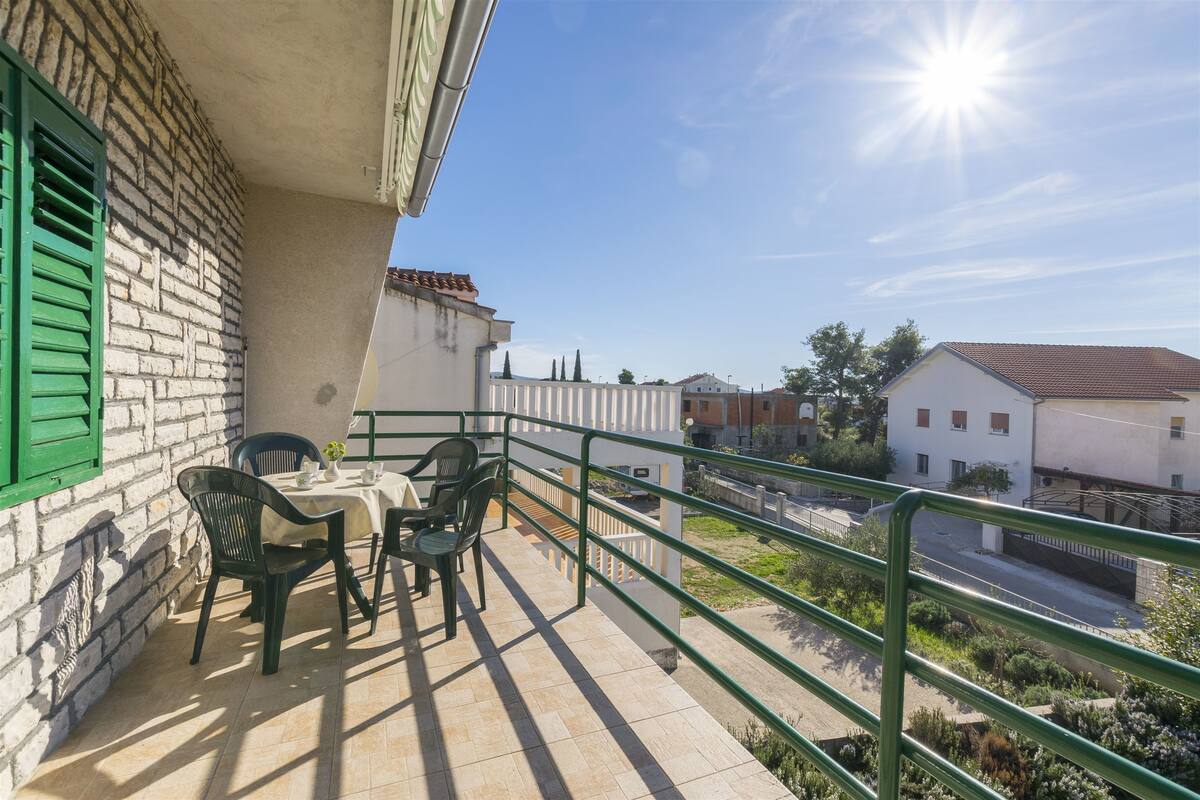 Ein Balkon mit Tisch und Stühlen, Blick auf die Straße und ein klarer Himmel.