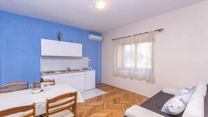 Un ambiente compatto con angolo ristoro, angolo cottura e divano con cuscini.