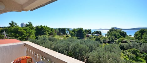 A balcony with a table and chairs, overlooking a lush green landscape and a body of water.