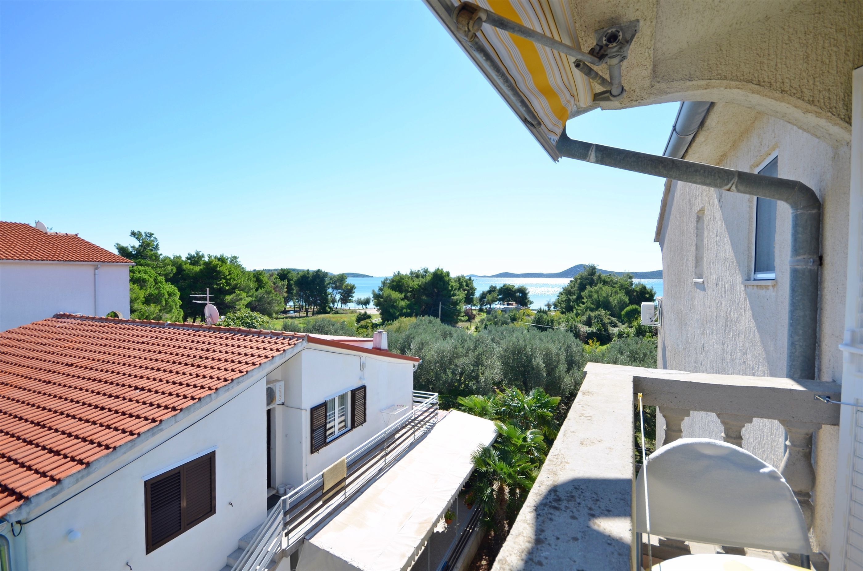 A balcony with a view of a coastal landscape, including buildings and greenery.