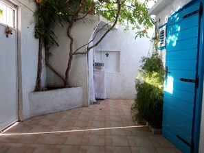 Enclosed courtyard with a tree, table, and blue door.