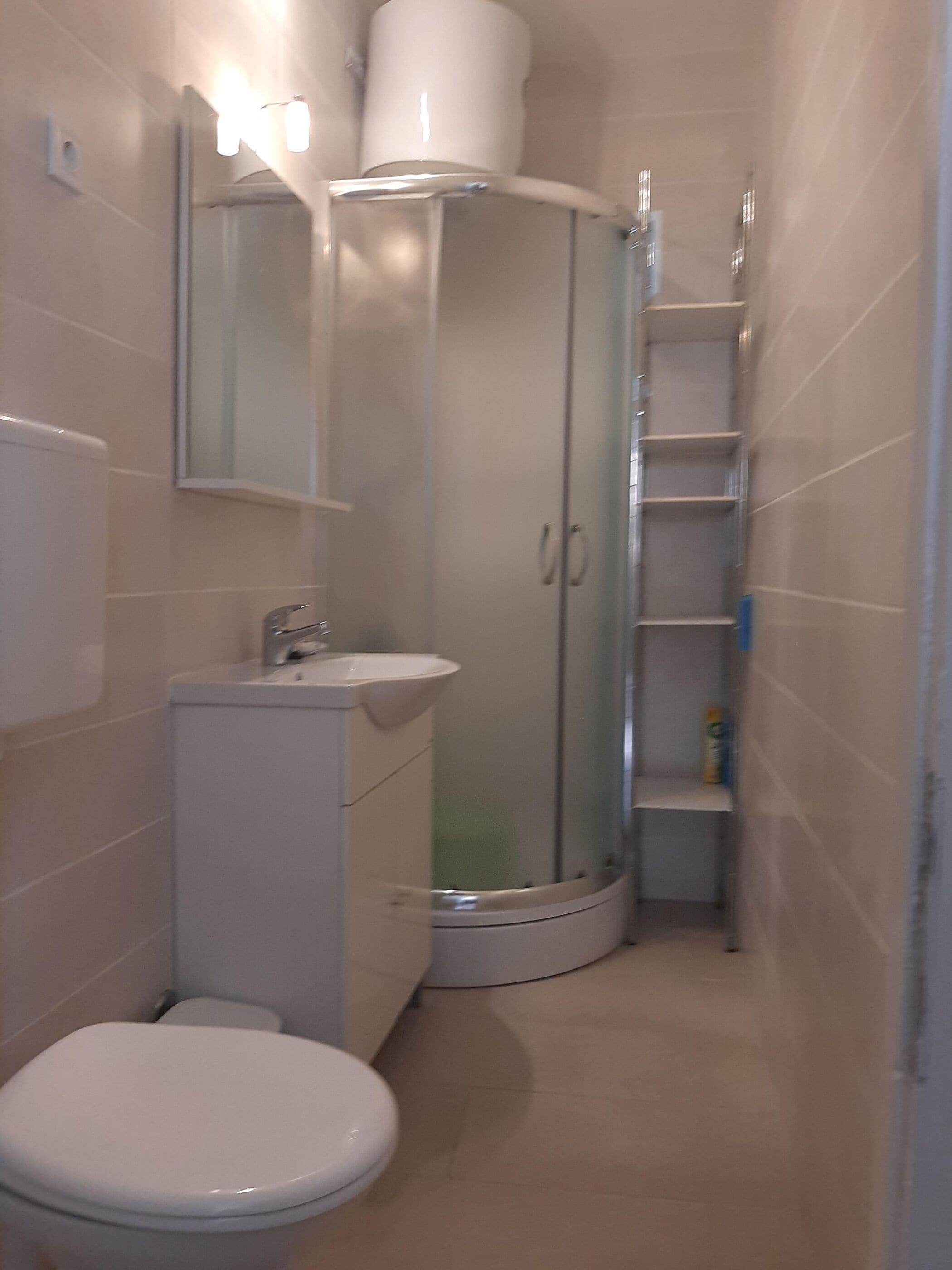 Un bany amb vàter, rentapel i plat de dutxa amb envàs de vidre.