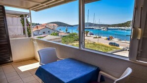 Een balkon met een tafel en stoelen, met uitzicht op een jachthaven vol boten en een kustplaats.