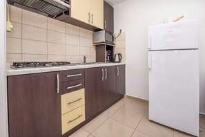 Una cocina equipada con estufa a gas, microondas, cafetera y un refrigerador blanco.