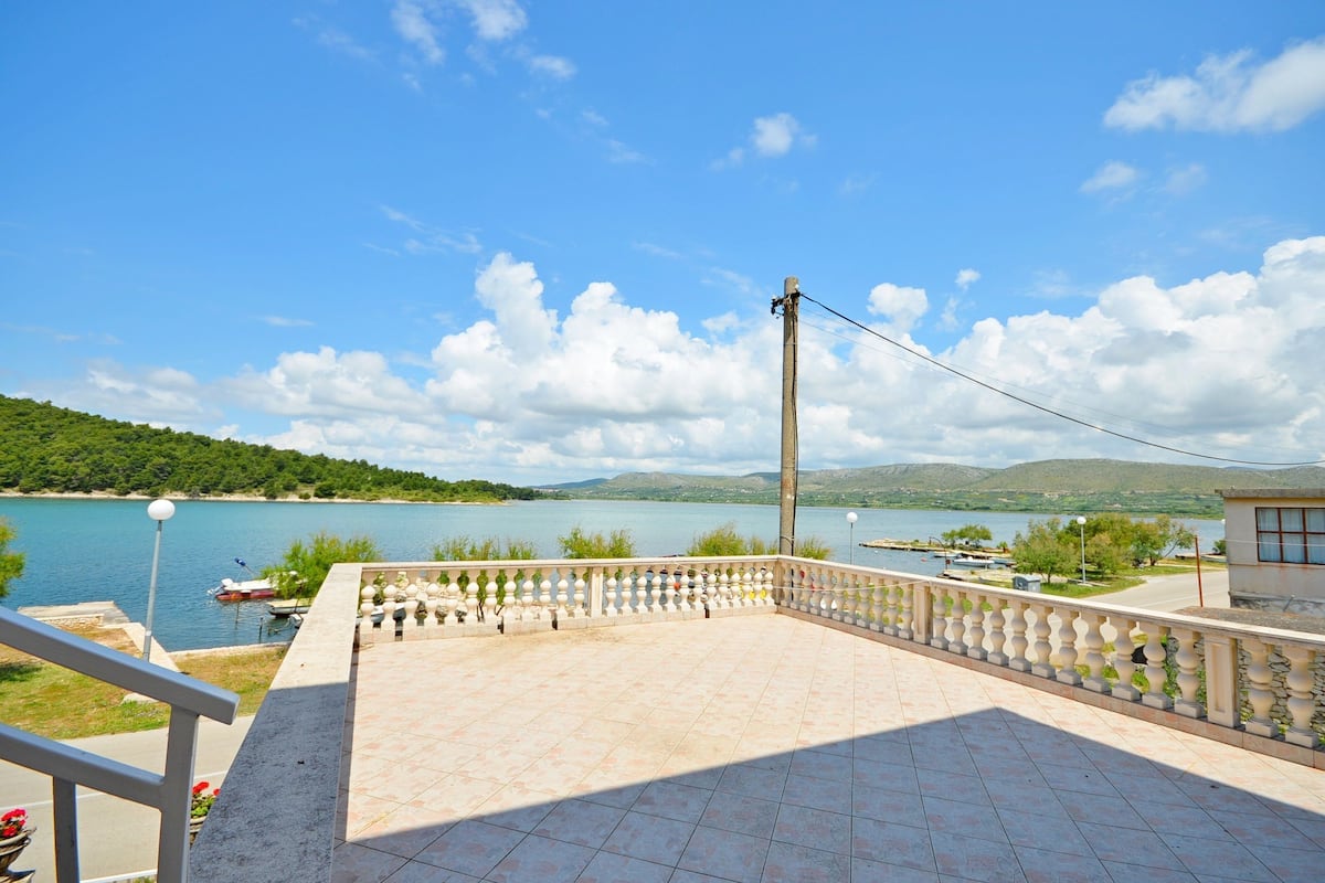 Eine Terrasse mit Blick auf einen See, einen Bootssteg und eine Steinmauer.