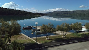 A calm lake with boats docked, surrounded by trees and a clear sky. - Apartments Vila Punta (Jadrtovac)