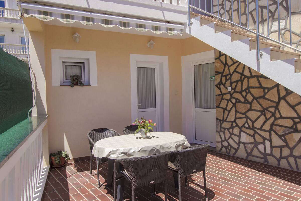 A patio with a table and chairs, a potted plant, and a stone wall.