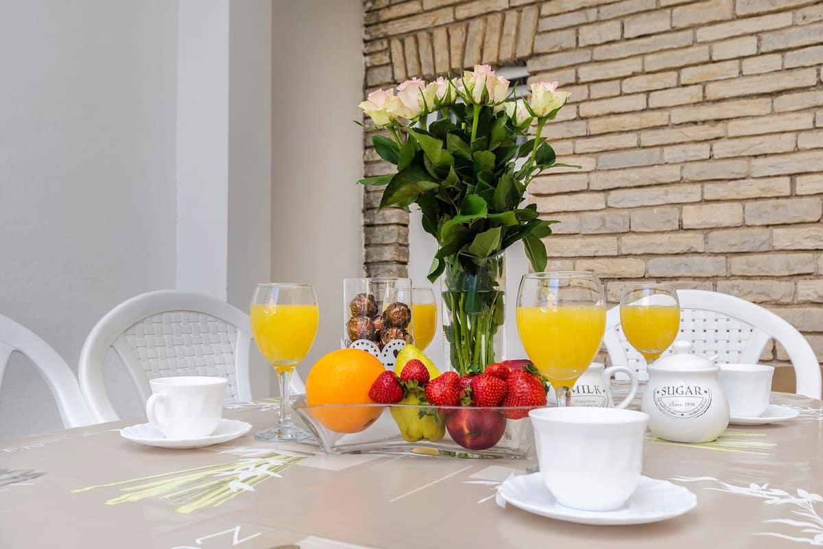 A breakfast table with fruit, juice, and a sugar pot.