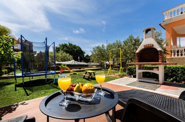 Un patio exterior con una mesa lista para el desayuno, un trampolín y un horno de ladrillo.