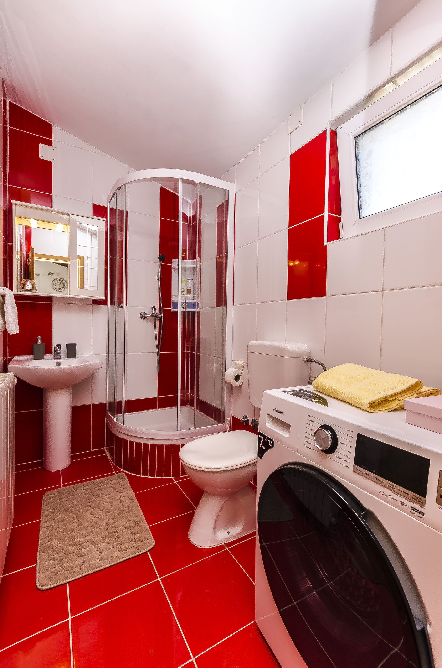 Un baño con ducha, inodoro, lavamanos y lavadora.
